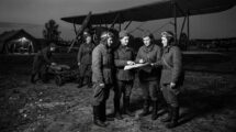 Soviet Night Witches female pilots and crew preparing for a night mission next to a Polikarpov Po-2 bomber. Four pilots are studying a map while a ground crew member pushes a bomb cart.